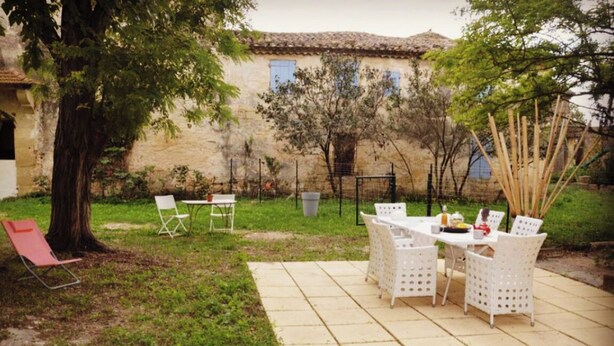 Eine Terrasse im Freien mit Tisch und Stühlen, einem Baum und einem Gebäude im Hintergrund.