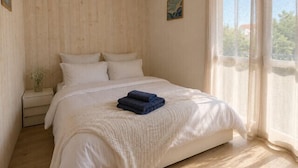 A bedroom with a bed, a nightstand, a window with curtains, and a painting on the wall. - Bright and well decorated nest in La Rochelle (La Rochelle)