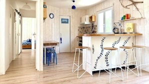 A kitchen with a wooden floor, a bar area with stools, a window, and a door. - Bright and well decorated nest in La Rochelle (La Rochelle)