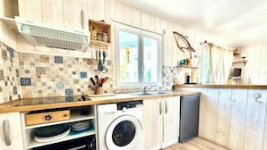 A compact kitchen with a washing machine, oven, and a window with curtains. - Bright and well decorated nest in La Rochelle (La Rochelle)