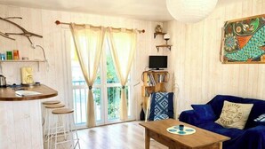 A living room with a sofa, a coffee table, a bar area with stools, and a television. - Bright and well decorated nest in La Rochelle (La Rochelle)