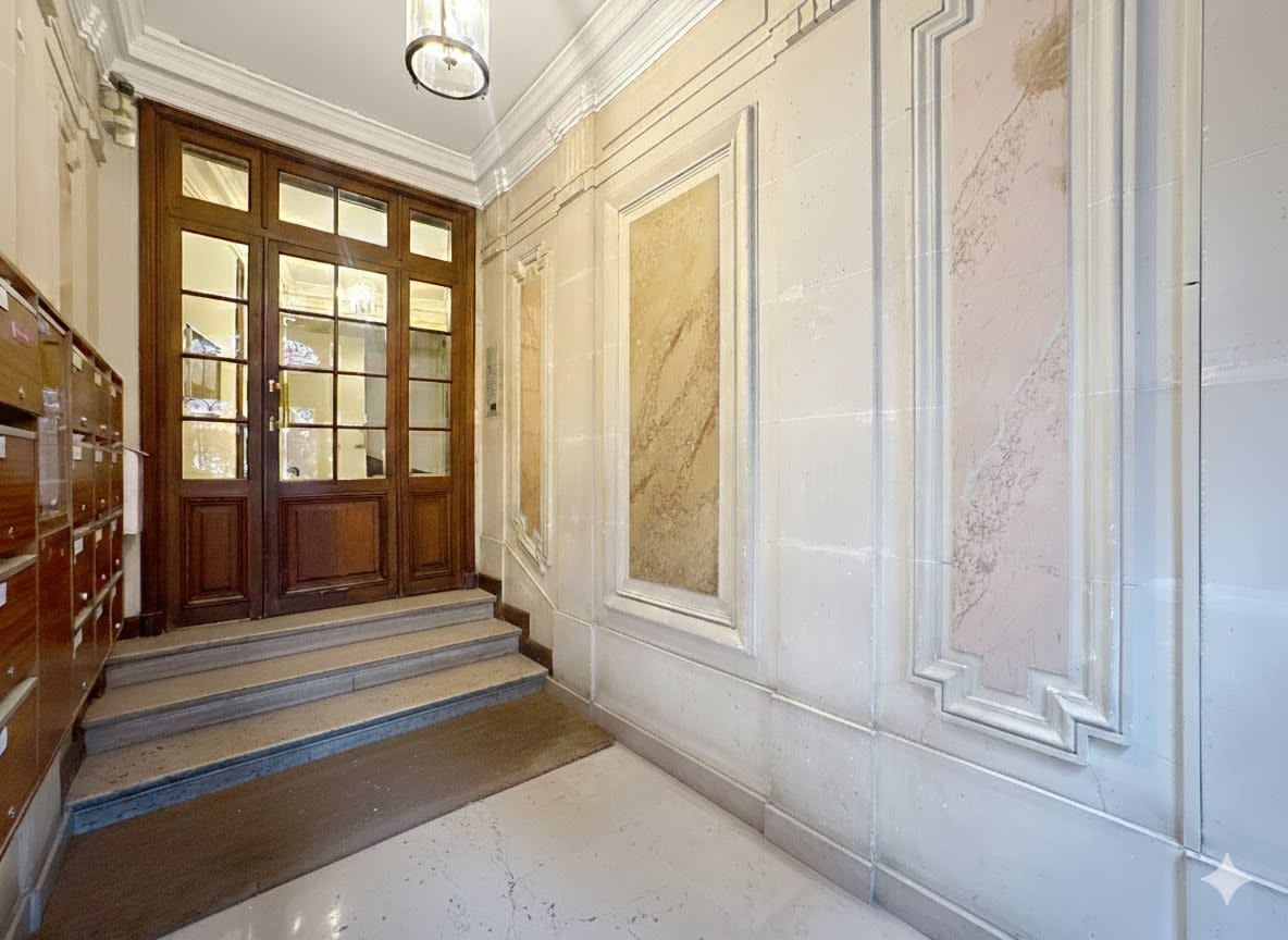 A grand staircase with a wooden door and marble walls.