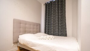 A single bed with a headboard, a window with curtains, and a wooden floor. - Apartment near Montmartre (Paris)