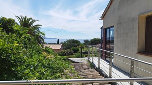 A staircase leading to a balcony with a view of the sea and surrounding greenery. - Modern cocoon with garden and beautiful sea view (Cavalaire-sur-Mer)