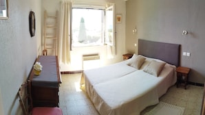 A bedroom with a bed, a desk, a chair, a window with curtains, and a ladder. - Modern cocoon with garden and beautiful sea view (Cavalaire-sur-Mer)