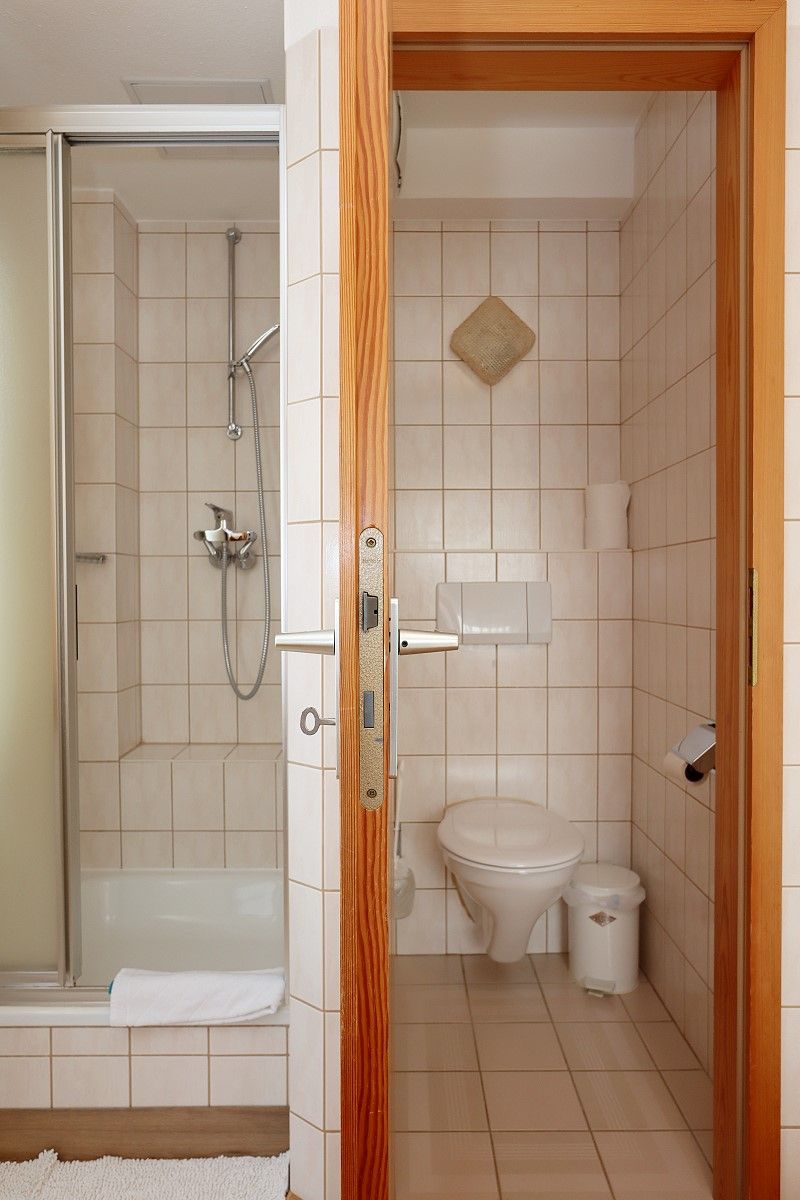 Casa de banho com chuveiro, sanita e um porta-toalhas.