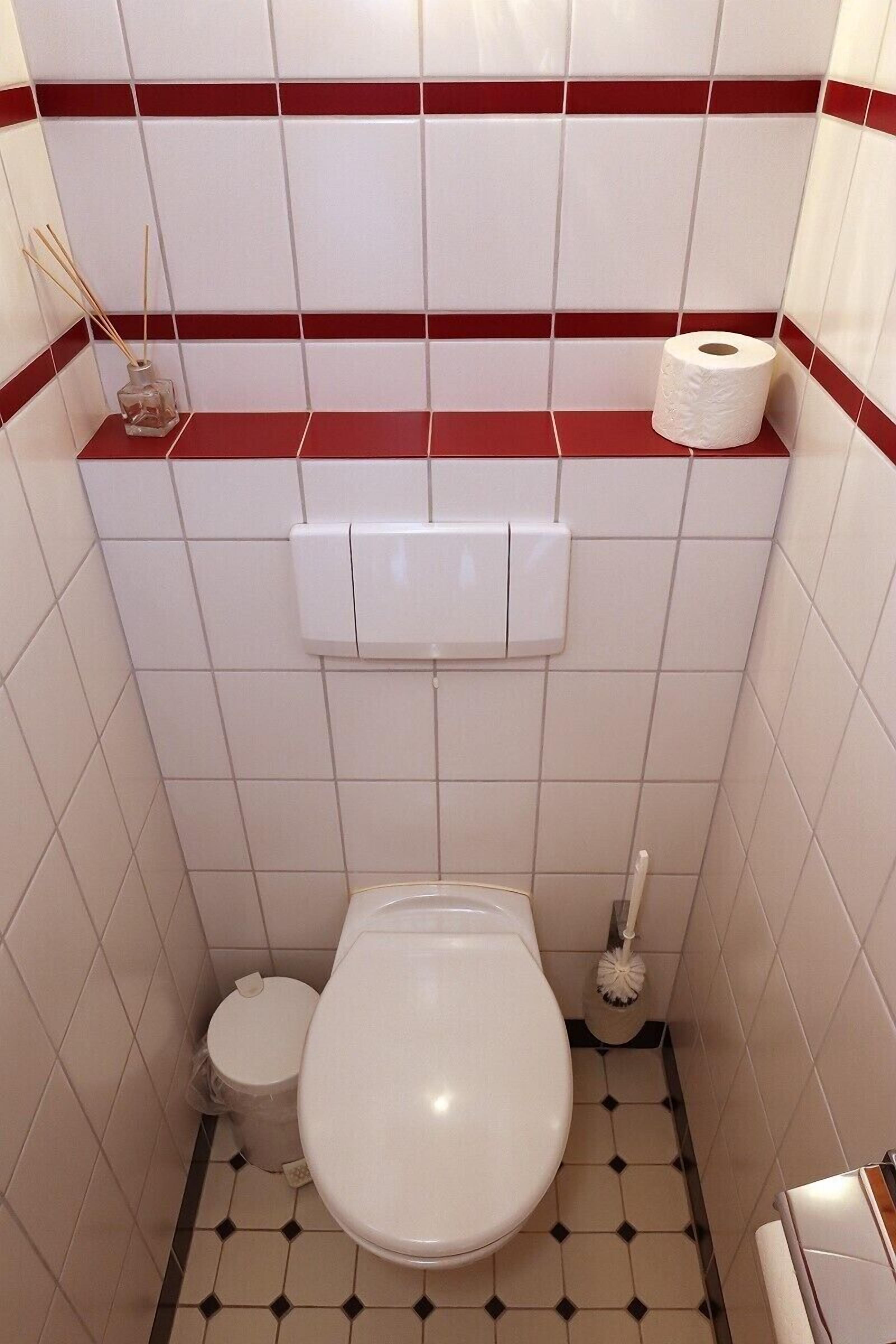 A small, tiled bathroom with a toilet, bidet, and a toilet paper holder on the wall.