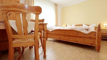 Una cama de madera en una habitación con una silla de madera y una mesita.