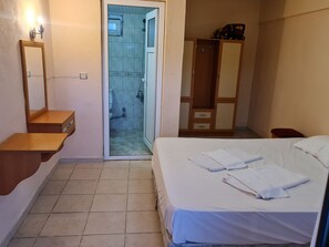 Una camera da letto con un letto, un armadio in legno, uno specchio e un angolo doccia.