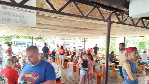 An outdoor dining area with wooden benches and tables, covered by a metal roof structure. - CANER MOUNTAIN HOTEL (Kemer)