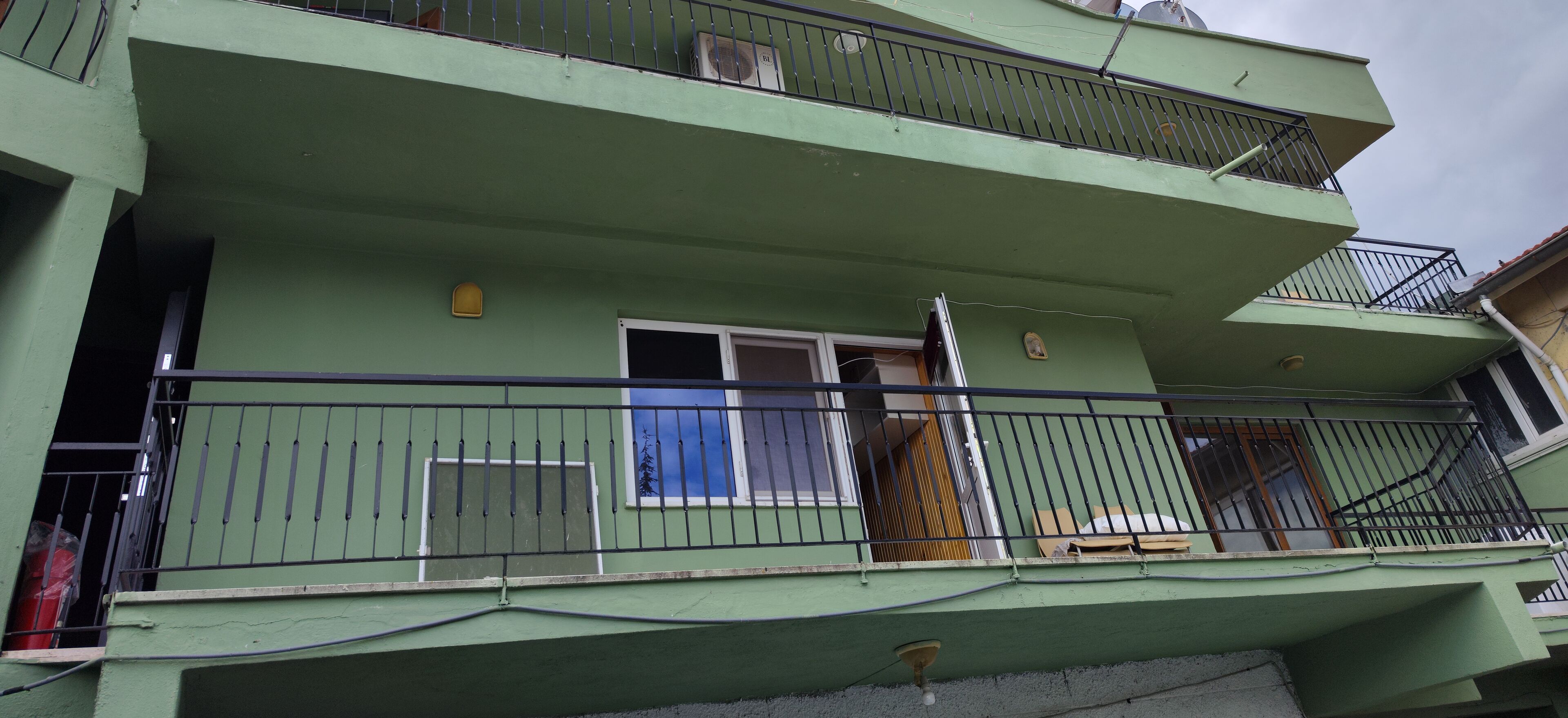 A multi-story building with balconies, a window with a wooden blind, and a door with a metal handle.