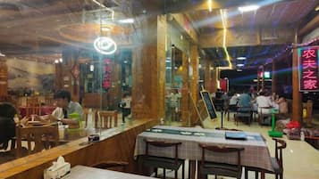 Interior de restaurante con mesas y sillas de madera, una barra y letreros de neón.