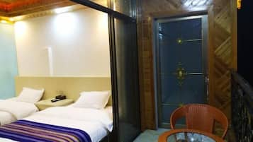 A hotel room with two beds, a glass table, and a door with a decorative handle.
