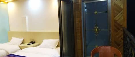 A hotel room with two beds, a glass table, and a door with a decorative handle.