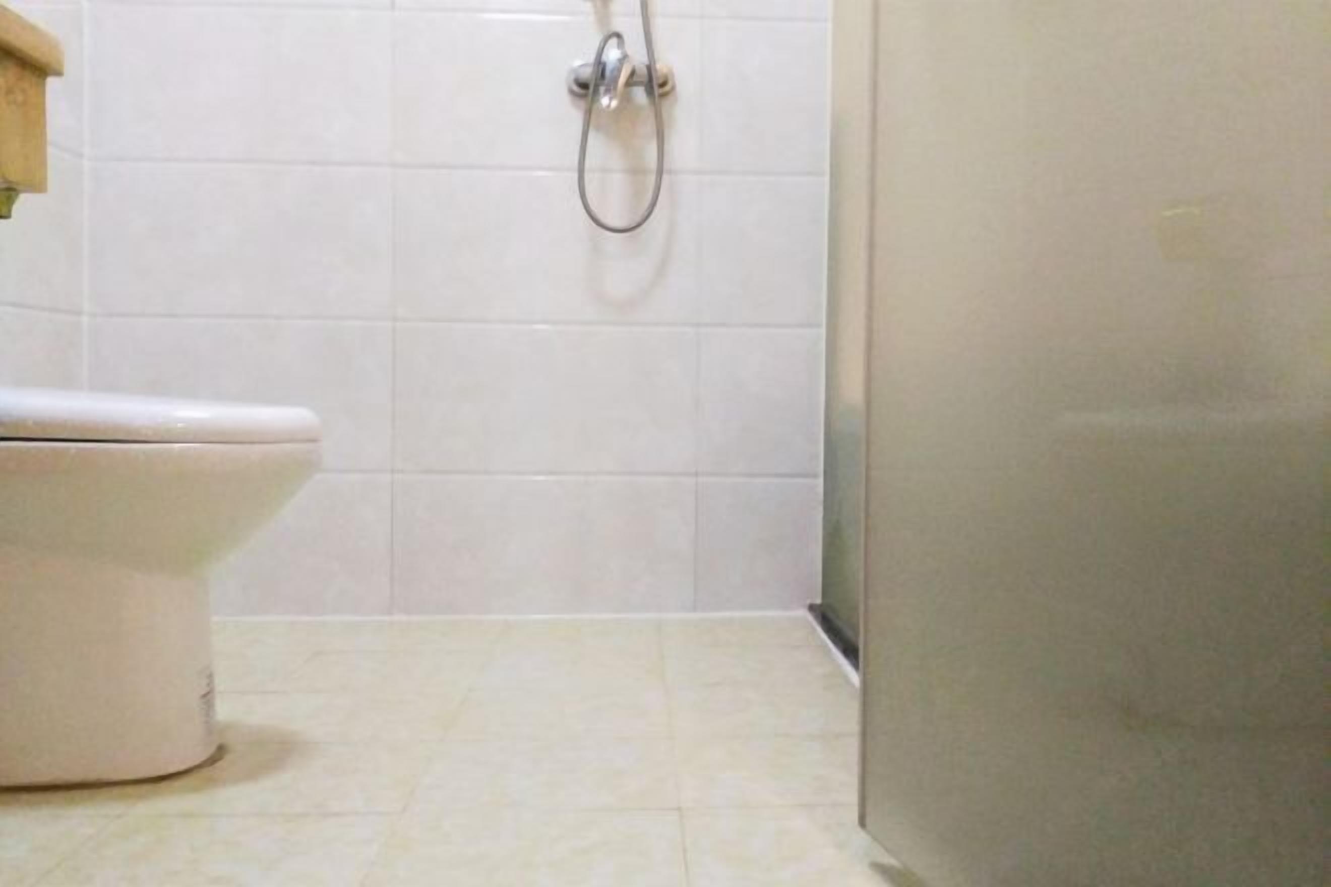 Une salle de bain avec des toilettes, une douche et des murs carrelés.
