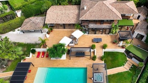 A large house with a swimming pool, multiple outdoor seating areas, and a well-maintained garden.