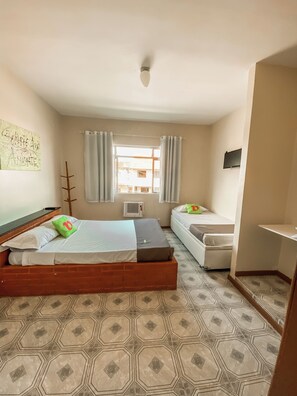 A room with a bed, a smaller bed, a TV, and a window with curtains. - Pousada Aguas do Pero (Cabo Frio)