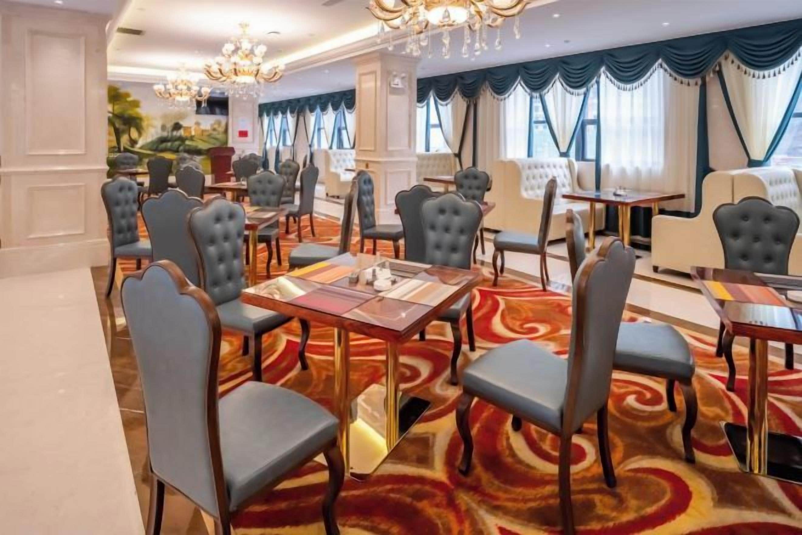 A hotel dining area with round tables, chairs, and a patterned carpet.