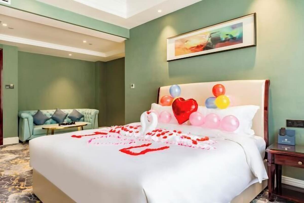 Une chambre d’hôtel avec un grand lit, un canapé et un tableau au mur.