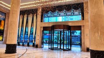 A lobby with marble columns, a revolving door, and a view of the outside.