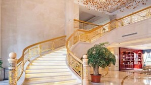 A grand staircase with ornate railings and a potted plant at the landing. - Nujiang East Wenhao hotel (Lushui)