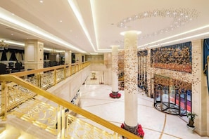 A grand hotel lobby with a central staircase, multiple levels, and a decorative ceiling. - Nujiang East Wenhao hotel (Lushui)