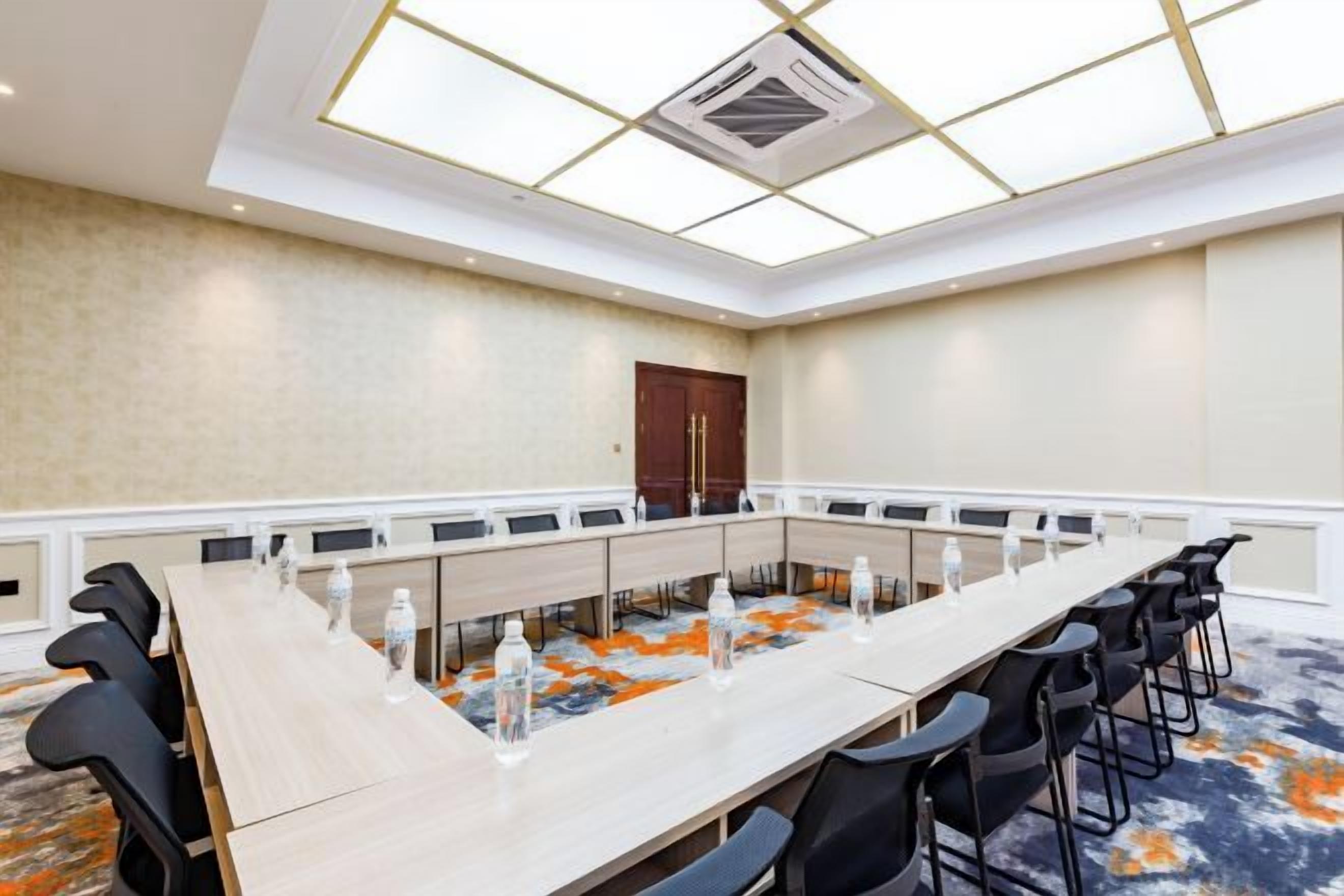A conference room with a long table, chairs, and a ceiling light fixture.