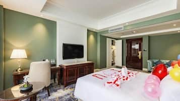 A hotel room with a bed, a TV, a desk, a chair, and a lamp.