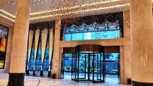 A spacious lobby with marble flooring, large columns, and a revolving door leading to an outdoor area. - Nujiang East Wenhao hotel (Lushui)