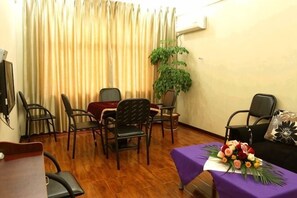 Une pièce comprenant une table à manger, des chaises, un canapé et une plante en pot.