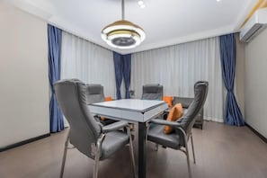 A modern dining area with a round table and four chairs, a ceiling light fixture, and blue curtains. - Home Inn Yubai Yun Hotel (Zhangjiagang Jingang Central Plaza) (Zhangjiagang)