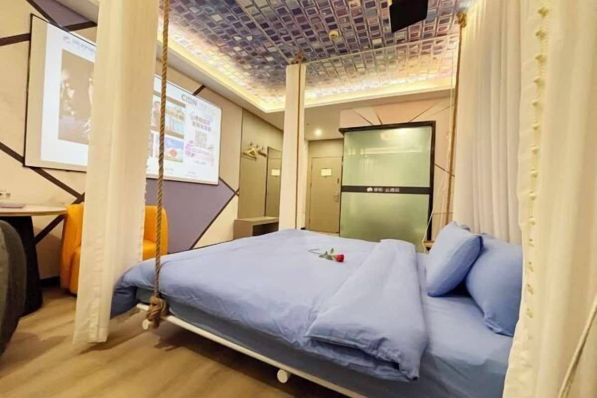 A hotel room with a bed, a desk, a chair, and a curtain.