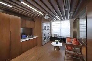 Cozinha moderna com eletrodomésticos embutidos, área de refeições com mesa redonda e uma janela grande que oferece iluminação natural.
