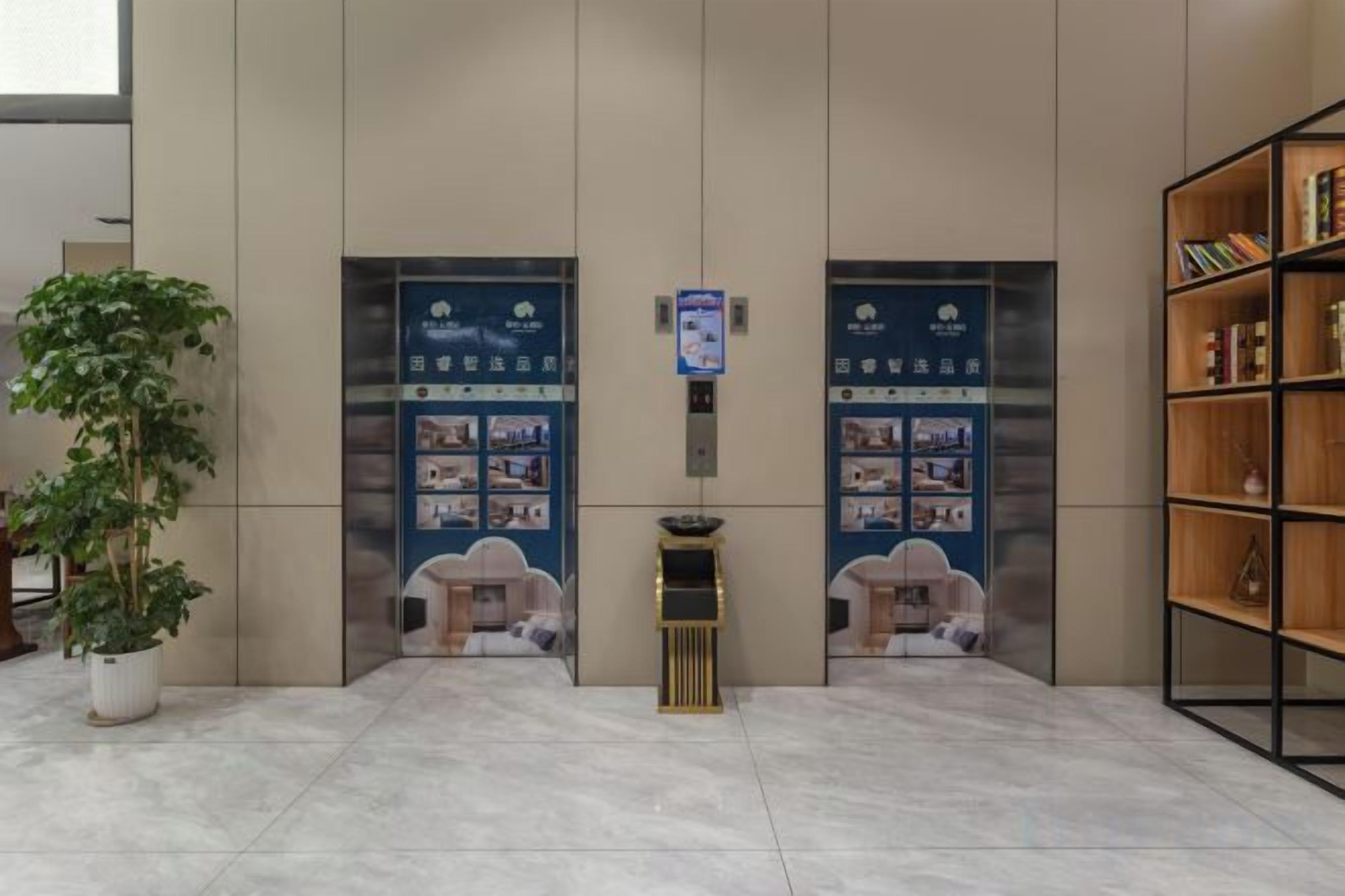 A reception area with a reception desk, two doors with informational posters, a potted plant, and a bookshelf.