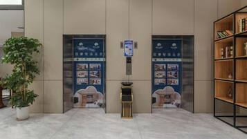 A reception area with a reception desk, two doors with informational posters, a potted plant, and a bookshelf.