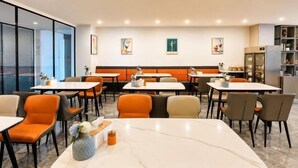 A restaurant with tables and chairs, a marble table in the foreground, and artwork on the walls. - Home Inn Yubai Yun Hotel (Zhangjiagang Jingang Central Plaza) (Zhangjiagang)