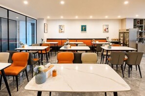 Ravintola, jossa on pöytiä ja tuoleja. Etualalla on marmoripöytä ja seinillä taideteoksia.