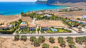 An aerial view of Villa Aqua Maris, featuring a cluster of buildings with a central courtyard, a swimming pool, and a view of the sea. - Villa Aqua Maris by Villa Plus (Rhodes)