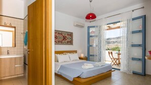 A bedroom with a bed, a nightstand, a red pendant light, a window with curtains, and a view of the outdoors.