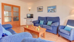 A living room with a sofa set, a coffee table, a television, and two framed pictures on the wall. - Villa Badia D'Or by Villa Plus (Cala d'Or)