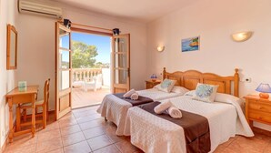 A bedroom with two beds, a balcony, and a view of the outdoors. - Villa Badia D'Or by Villa Plus (Cala d'Or)