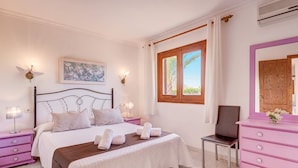A bedroom with a bed, a dresser, a chair, and a window with curtains. - Villa Bauza by Villa Plus (Mallorca)
