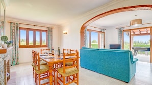 A dining area with a wooden table and chairs, a blue sofa, and a TV. - Villa Bauza by Villa Plus (Mallorca)
