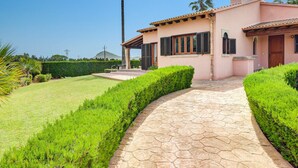 A pink house with a stone pathway leading to a covered patio area. - Villa Bauza by Villa Plus (Mallorca)