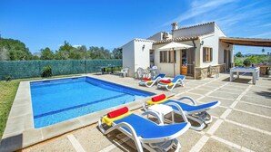 Una piscina con sillones de descanso y una terraza.