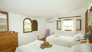 Een hotelkamer met twee bedden, een houten dressoir, een kaptafel met spiegel en een raam met gordijnen.