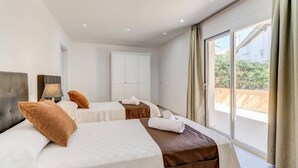 A hotel room with two beds, a wardrobe, and a balcony with a view. - Villa Zaragoza by Villa Plus (Cala Sant Vicenç)