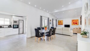 A modern kitchen with a dining area, a living room, and a TV. - Villa Zaragoza by Villa Plus (Cala Sant Vicenç)