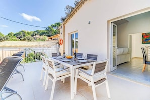 An outdoor patio with a table set for four, white chairs, and a view of the surrounding area.