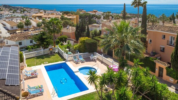 Ett bostadsområde med en swimmingpool, solpaneler och utsikt över havet.